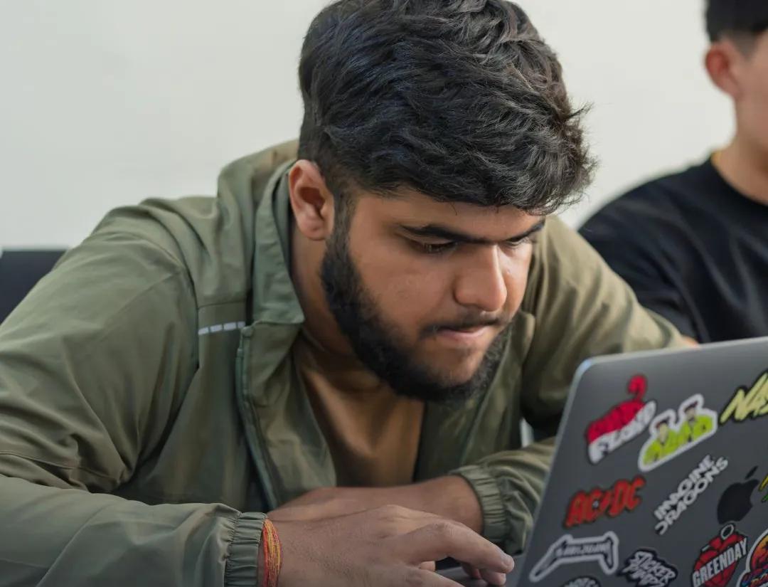 A student editing on a stickered laptop